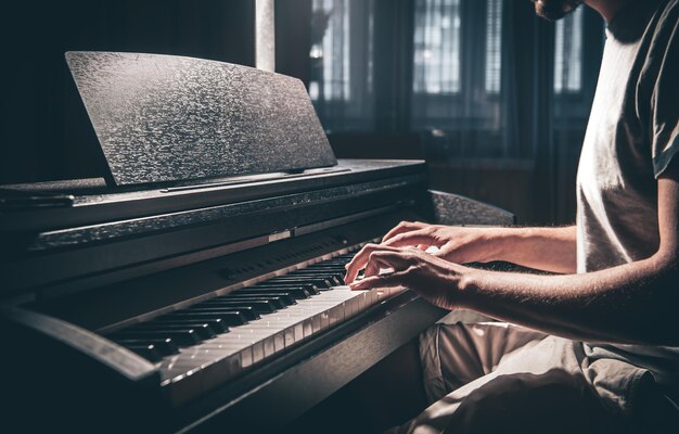 A man plays an electronic piano in a dark room