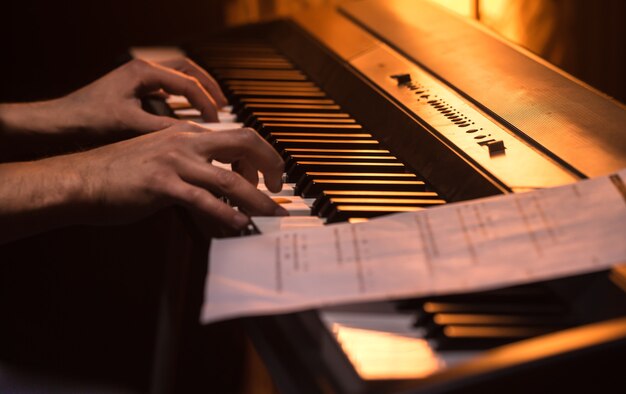 человек играет ноты на пианино, крупный план, красивый цветной фон, концепция музыкальной деятельности