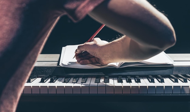 Un uomo suona il pianoforte e scrive su un taccuino al buio