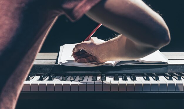 한 남자가 피아노를 연주하고 어둠 속에서 공책에 글을 씁니다.
