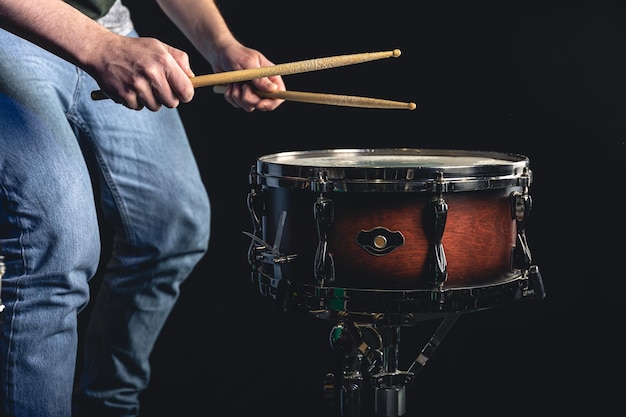 A man plays the snare drum against a dark background