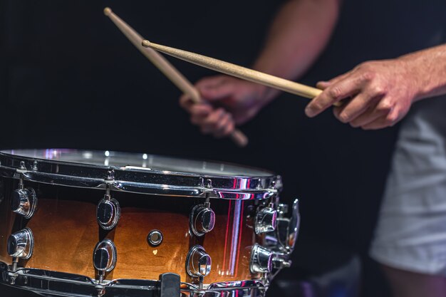 A man plays a snare drum with sticks, a drummer plays a percussion instrument, close up.