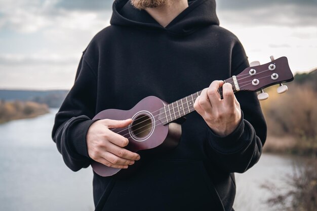 Free photo a man plays the ukulele guitar in nature closeup