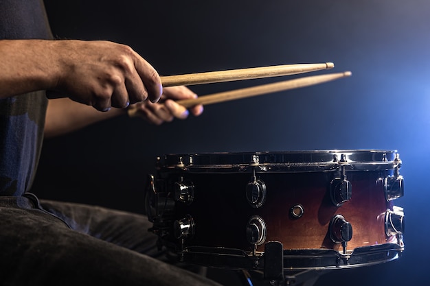 Un uomo gioca con i bastoni su un tamburo, un batterista suona uno strumento a percussione, primo piano.