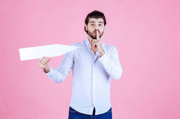 Man pointing himself with an arrow and asking for silence.