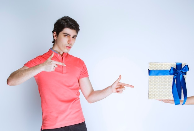 Man pointing at his white gift box with blue ribbon