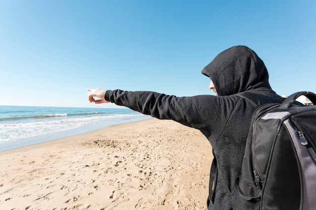 Foto gratuita uomo che indica in direzione del mare