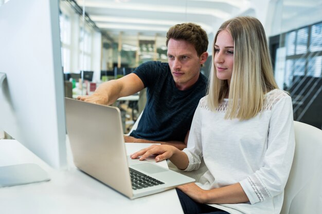 Man pointing at something on the screen of a woman