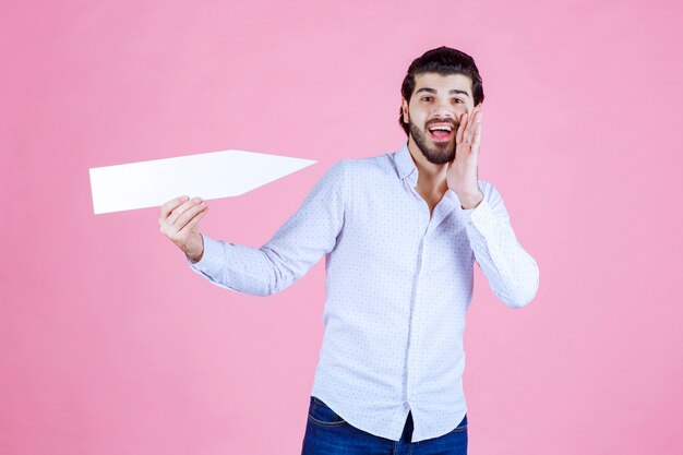 Man pointing a white arrow to himself and whispering.