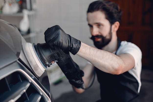 Free photo man polish a car in a garage