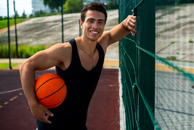 Man posing for the camera standing by the fence 