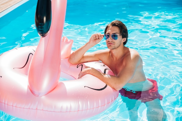 Man posing on flamingo swim ring