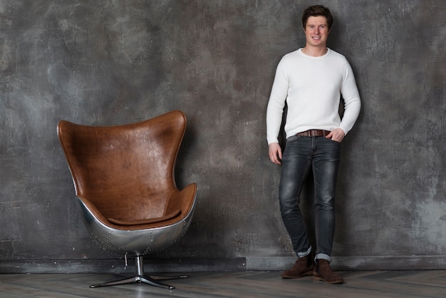 Man posing next to leather chair