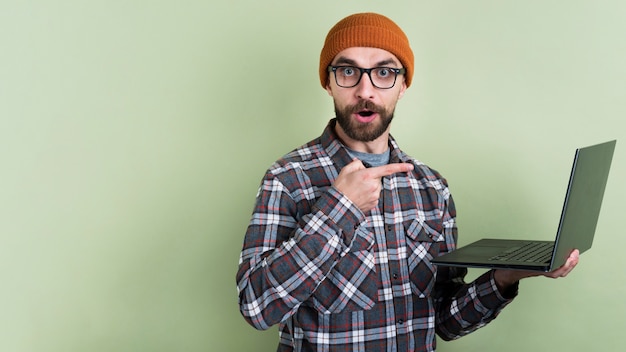 Free photo man posing and pointing at laptop