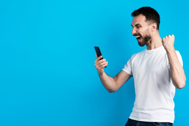 Man posing victorious while holding smartphone