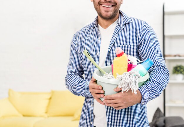 Man posing while holding bucket with cleaning products