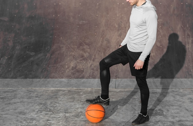 Free photo man posing with a basketball at his feet