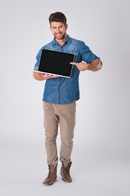 Бесплатное фото Мужчина позирует с джинсовой рубашкой и ноутбуком