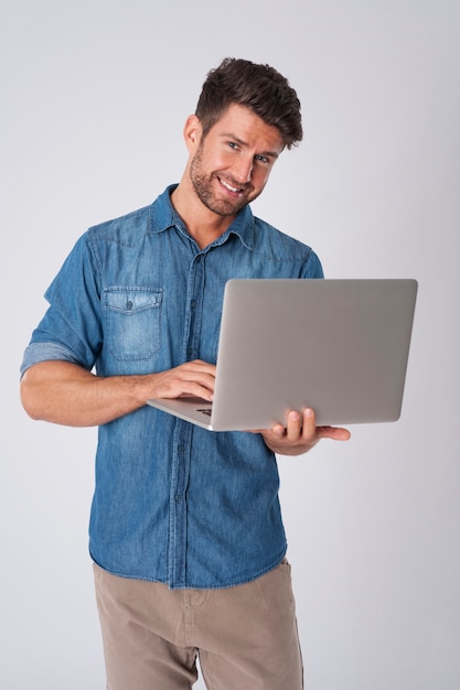 Uomo in posa con camicia di jeans e laptop