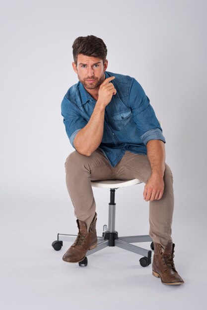 man posing with denim shirt sitting on a chair