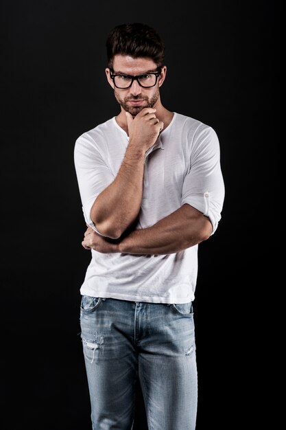 man posing with eyeglasses, jeans and white t-shirt