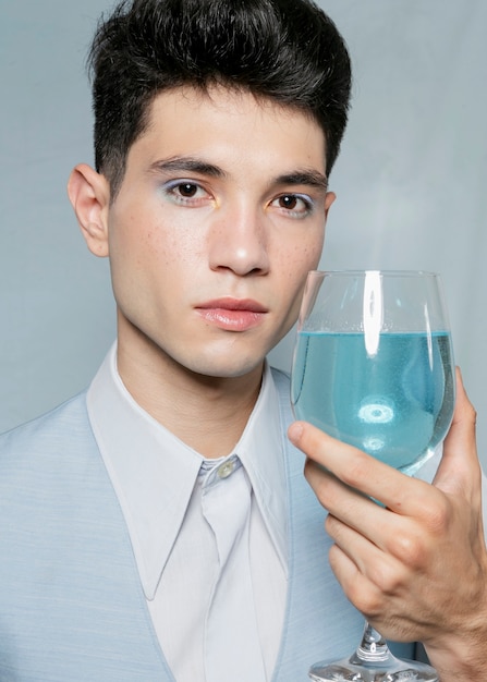 青い液体のガラスでポーズの男