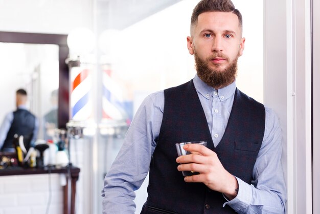 Man posing with his drink in a salon