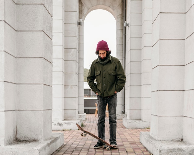 Foto gratuita uomo in posa con il suo skateboard in città