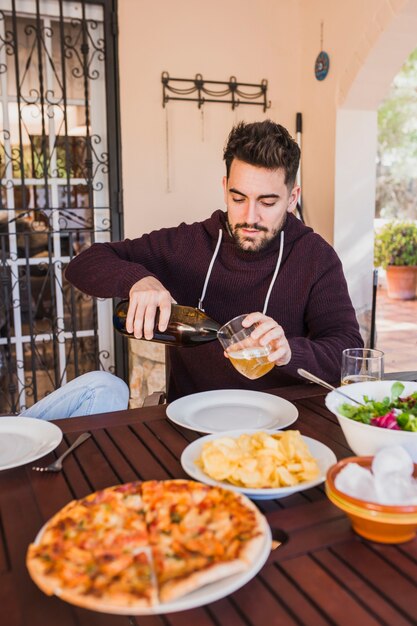 Man pouring beer into glass sitting at table