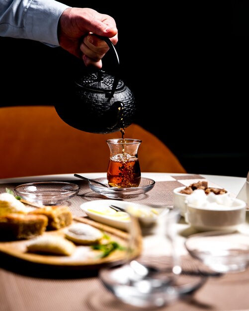 Man pouring black tea in the armudy national glass side view