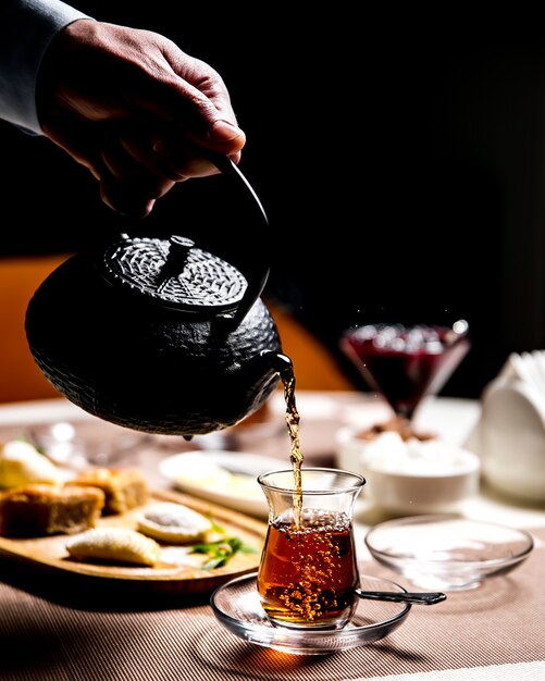 Man pouring black tea in the armudy national glass side view