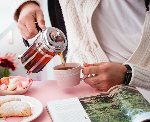 Man pouring black tea into a cup from french express