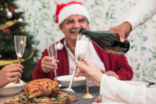 Man pouring champagne in glass at festive table 