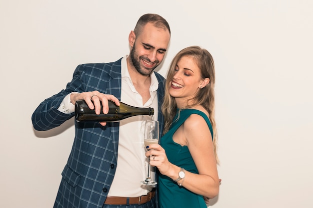 Uomo che versa champagne in un bicchiere di donna