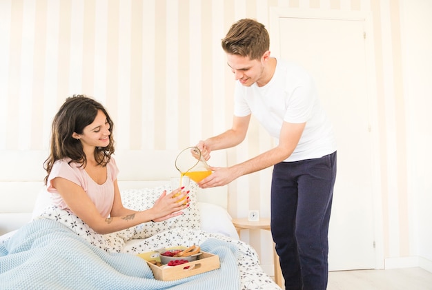 Man pouring juice for woman