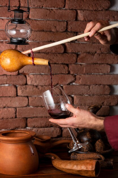 man pouring red wine from the wood bottle into glass