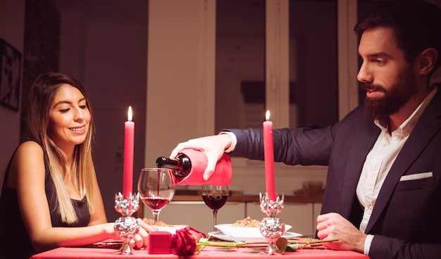 Free photo man pouring red wine in glass of woman