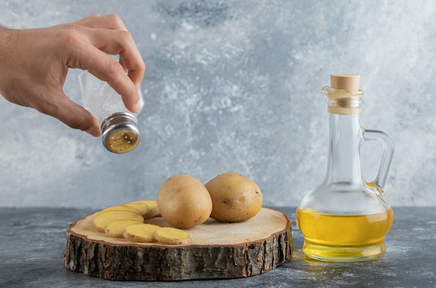 Free photo man pouring salt on sliced potato.