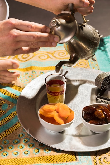 Free photo man pouring tea in tiny cup high view