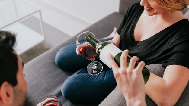 Man pouring wine to girlfriend on couch