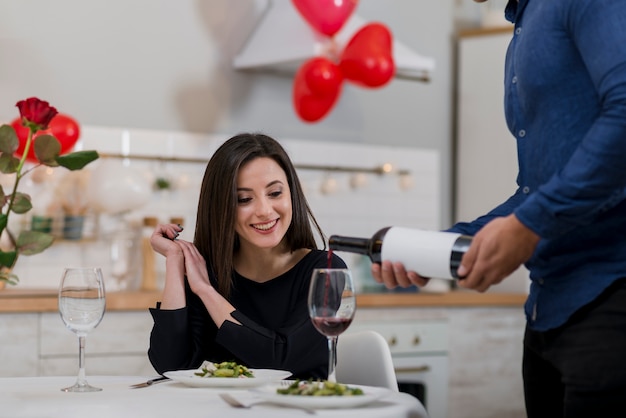 Man pouring wine in a glass for his girlfriend