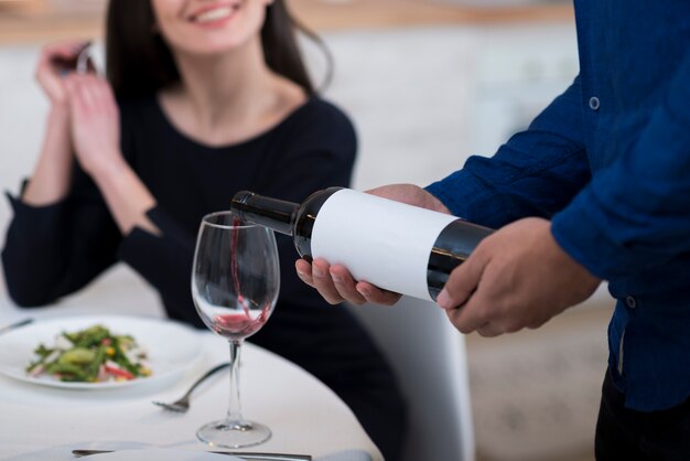 Man pouring wine in a glass for his wife