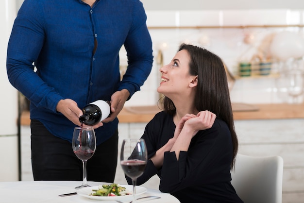 Foto gratuita uomo che versa il vino in un bicchiere per sua moglie