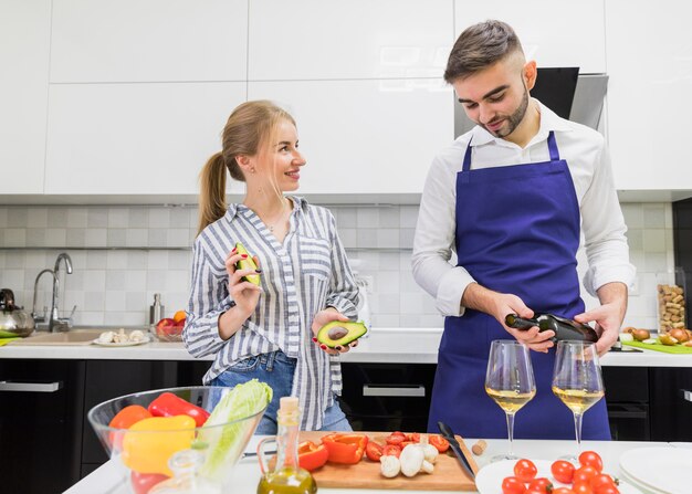 Man pouring wine in glass near woman with avocado 