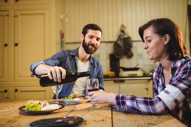 Man pouring wine in glass to woman