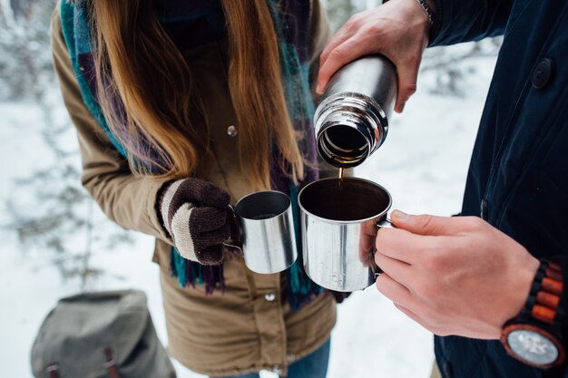 Man pours hot tea from thermos in mug. Closeup