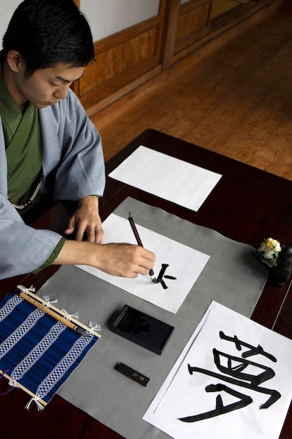 Man practicing japanese handwriting with an assortment of tools