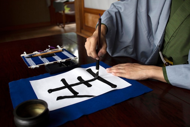 Man practicing japanese handwriting with an assortment of tools