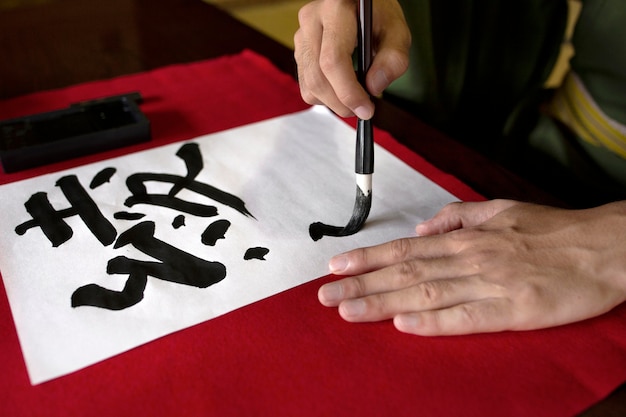 Man practicing japanese handwriting with an assortment of tools