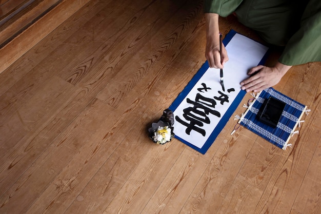 Man practicing japanese handwriting with an assortment of tools